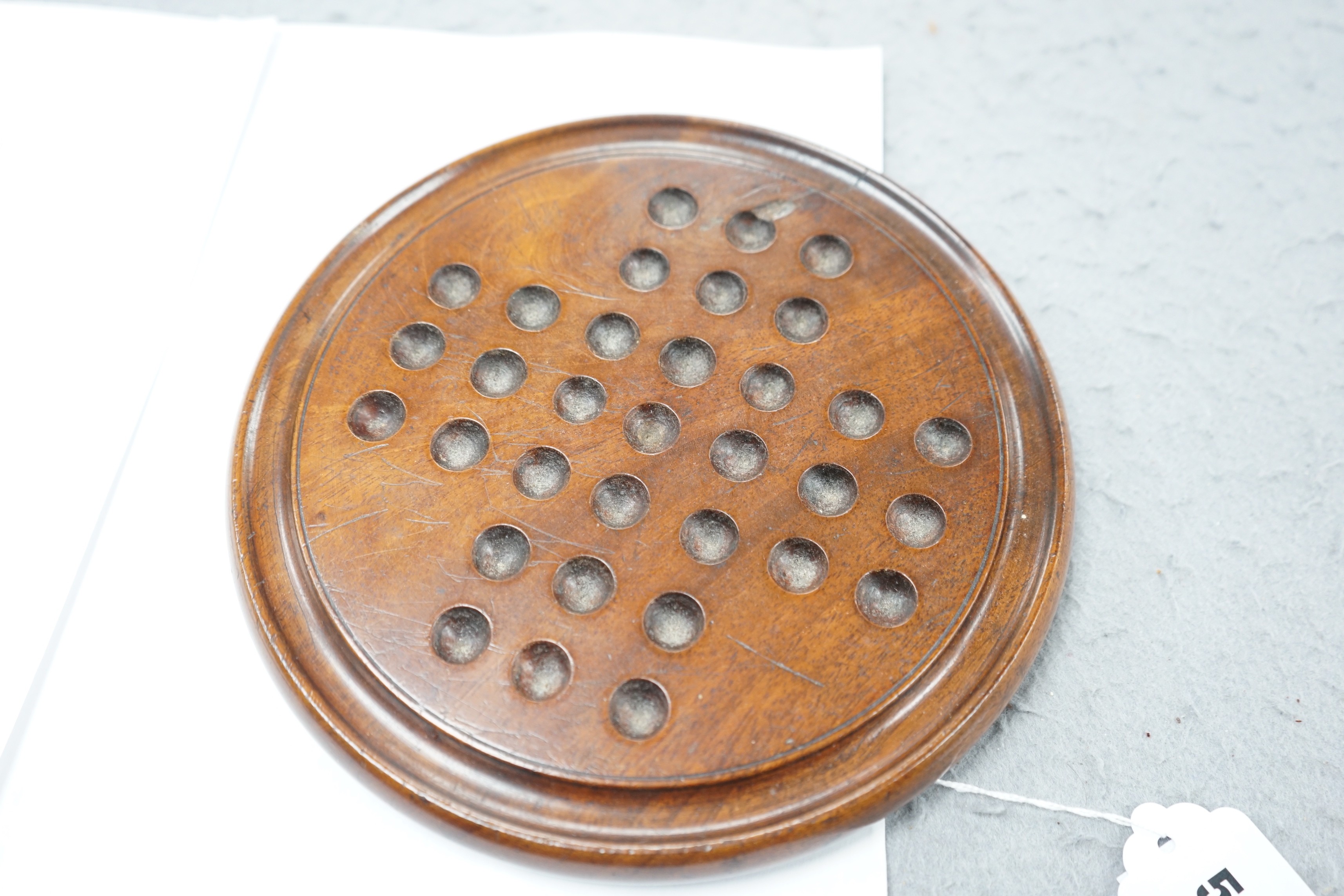 A mahogany solitaire board with a collection of latticino and marbled glass marbles